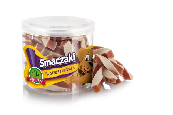 Przezroczysty słoik z żółtą etykietą marki stoi na białym tle, a obok niego piętrzą się ukośnie ścięte kawałki w jasnokremowe i pomarańczowe pasy.